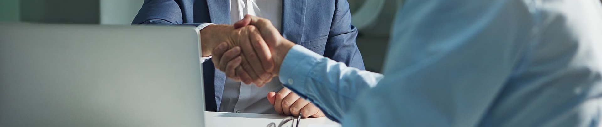 Twee mannen schudden de hand op een kantoor achter een bureau